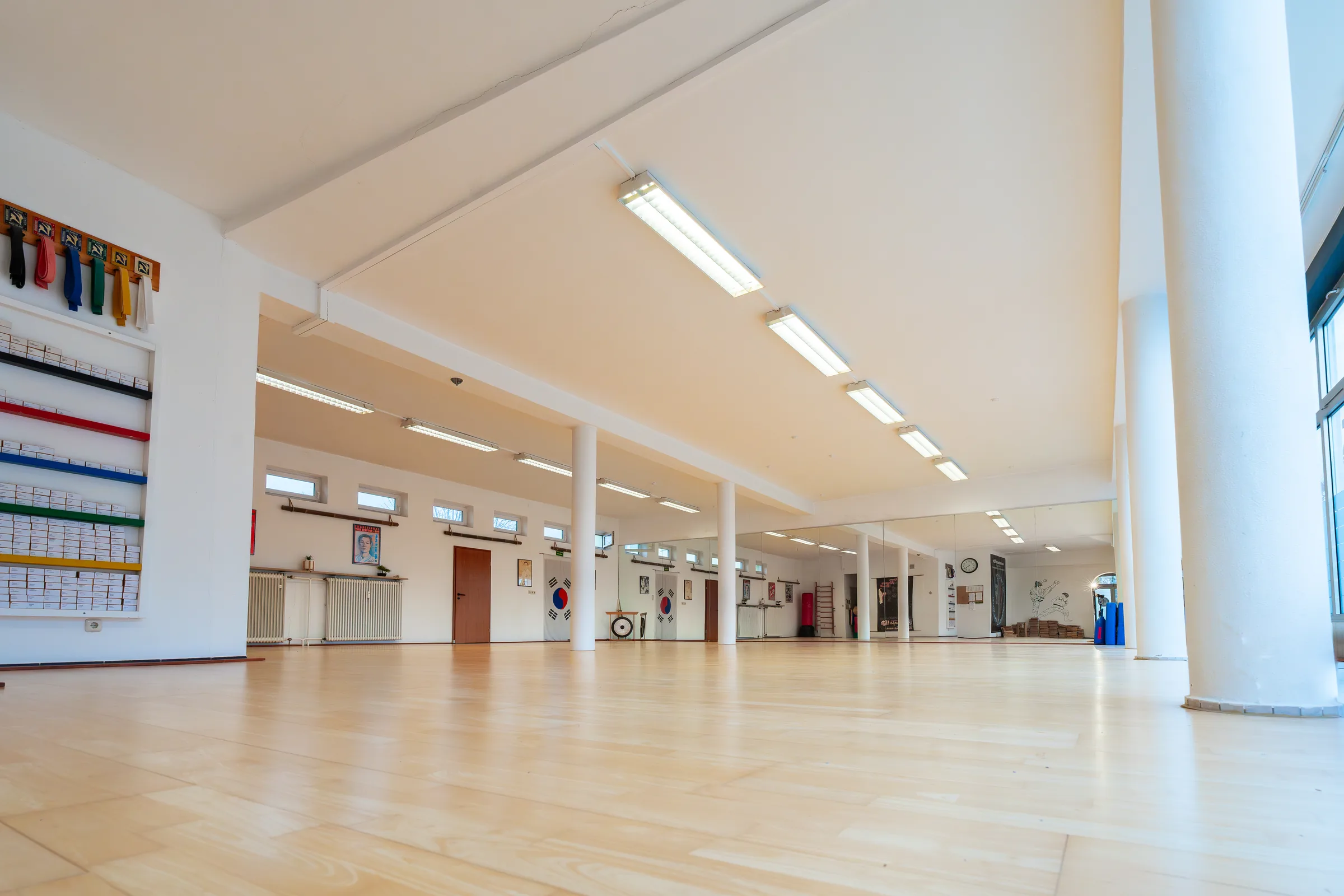 Die helle Trainingshalle des Taekwon-Do Center FFB mit Spiegelwand und Gürtelwand