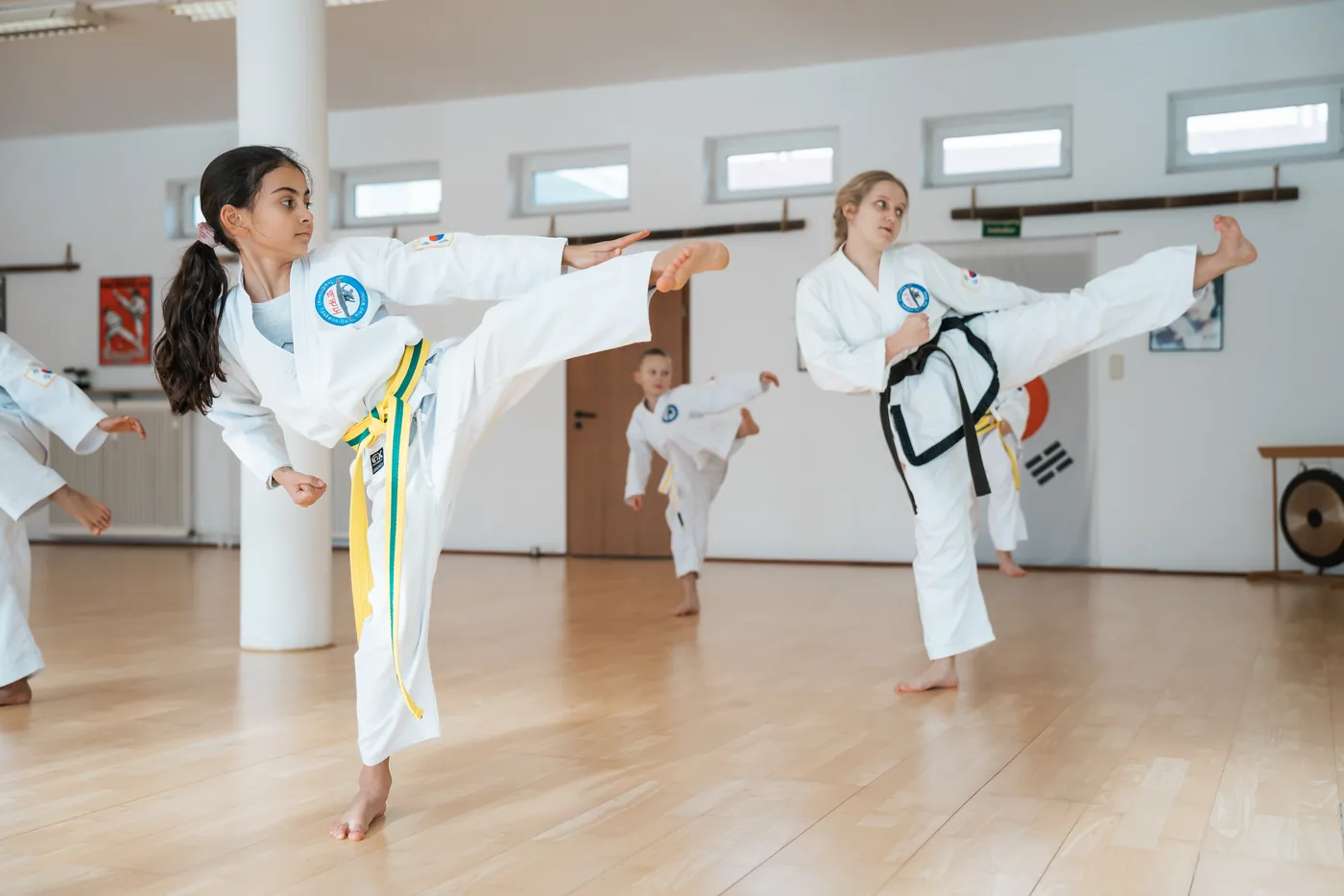 Zwei Mädchen in Taekwon-Do-Anzügen führen gleichzeitig einen hohen Seitwärtskick aus